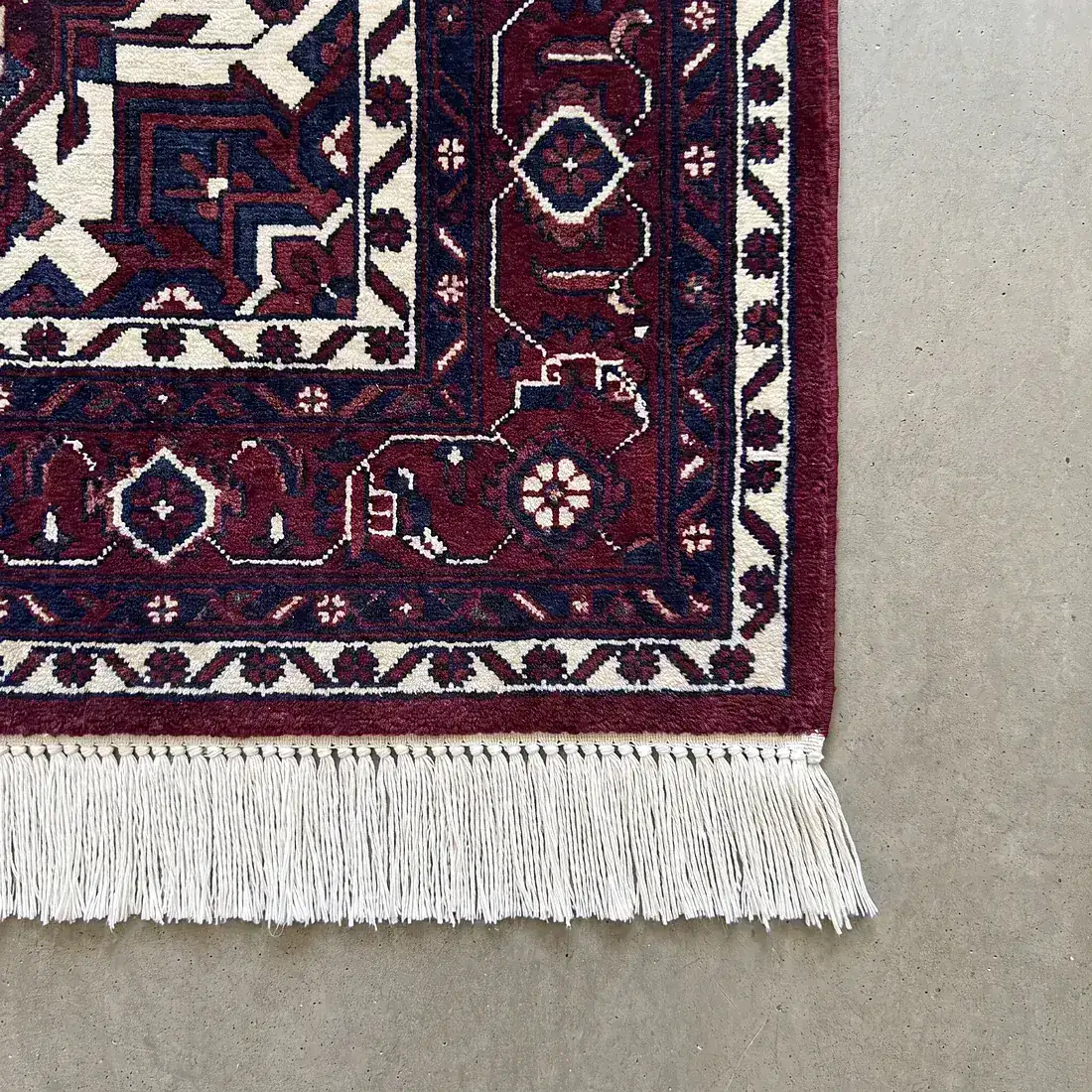Angle d'un tapis d'Orient restauré : bordure nette, franges refaites en coton