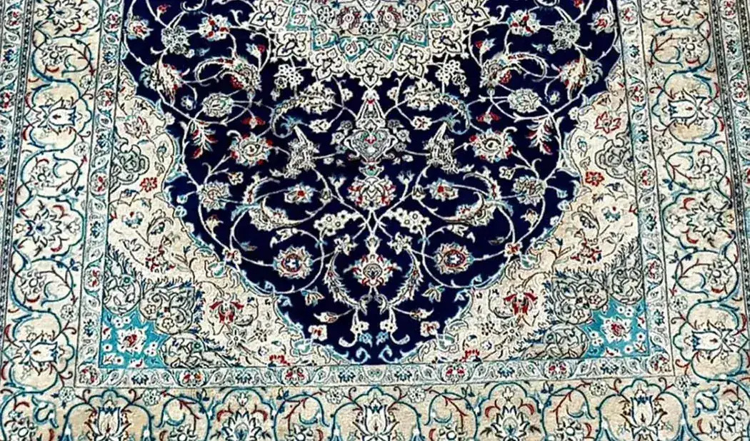 Tapis Nain après lavage à l'eau en atelier : tache disparue, ivoire éclairci et bleu profond retrouvé