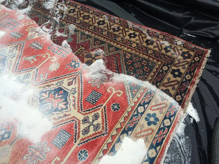 Tapis Kazak recouvert de mousse de shampooing pendant le nettoyage à l'eau