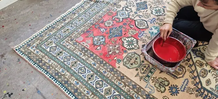 Artisan agenouillé lavant un tapis d'Orient à la main avec une bassine dans l'atelier