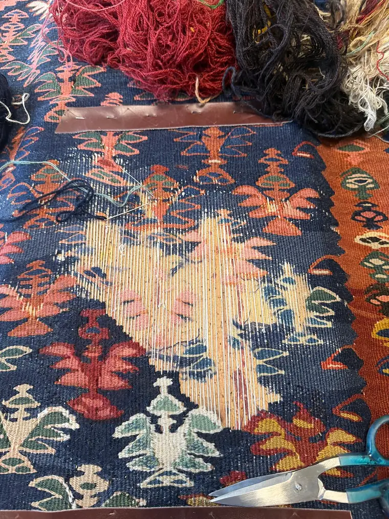 Kilim en restauration avec les écheveaux de laine teinte posés à côté