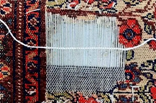 Chaîne et trame neuves tendues sur un trou de tapis persan avant retissage