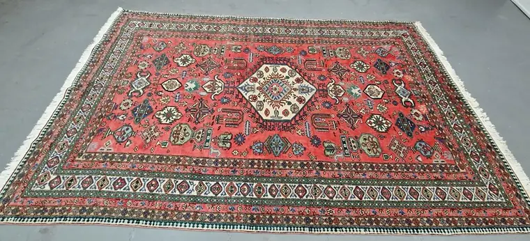Tapis Kazak ancien déroulé au sol pour expertise avant rachat